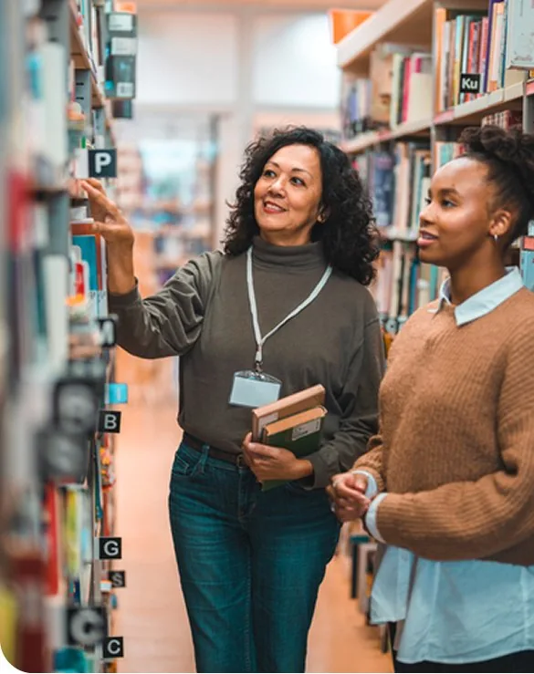 Two educators reviewing books together in a school library